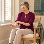 7 Aura-Cleansing Ideas for a Gentle Personal Reset Woman seated by a window making a small, relaxed hand movement above her forearm