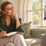 Clairvoyance Exercises: Visual Imagery, Observation and Choice A woman in a green blouse makes notes while observing a purple iris beside a window.