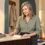 Protecting Your Psychic Energy: Optional Rituals and Practical Limits Woman with grey-brown hair beside a folded card and amethyst on an entryway console, with a blue phone nearby.