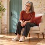 Opening Your Root Chakra Gray-haired woman sitting comfortably with her feet on the floor beside potted plants.
