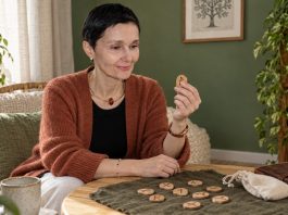Can Runes Heal? What Tradition and Evidence Really Say A woman reflecting on a wooden rune beside a rune set and cotton pouch.