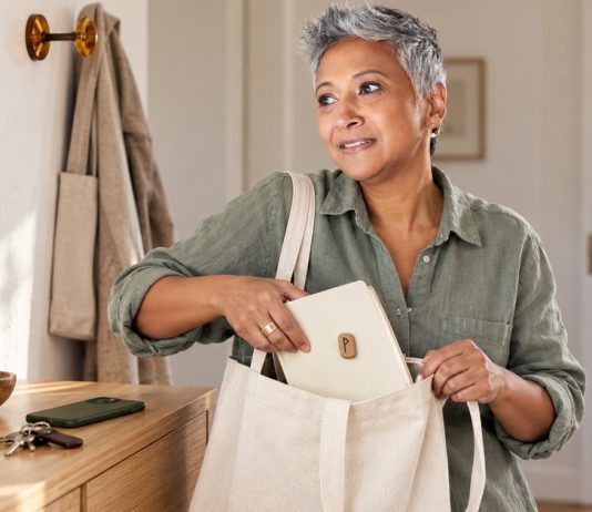 Using Runes Alongside Medical Care: A Safety Guide Woman packing a notebook with a small wooden rune reminder into a canvas bag