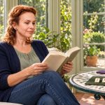The Runes Oracle: Ralph Blum’s Book and Personal Practice Woman reading a guidebook beside three marked rune tiles and a blank tile in a sunny conservatory